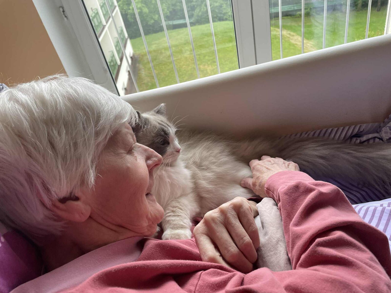 Seniorka odpočívá s kocourem u tváře